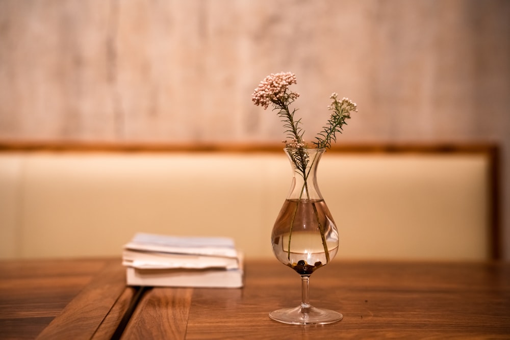 eine Glasvase mit Blumen darin auf einem Tisch