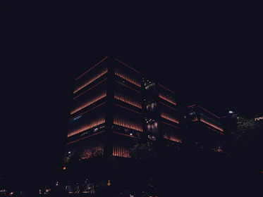 Modern residential building illuminated softly against a dark background with silver lettering.