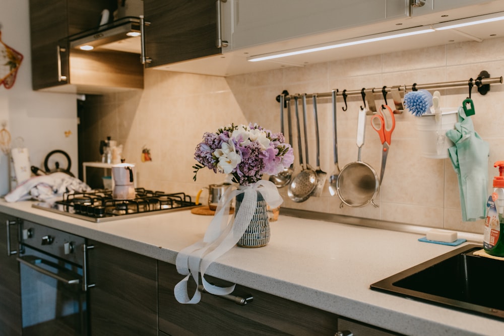a kitchen counter with a vase of flowers on it