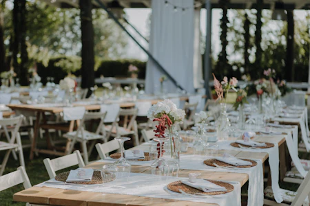 Long reception tables with white cloths and small flowers under a white tent