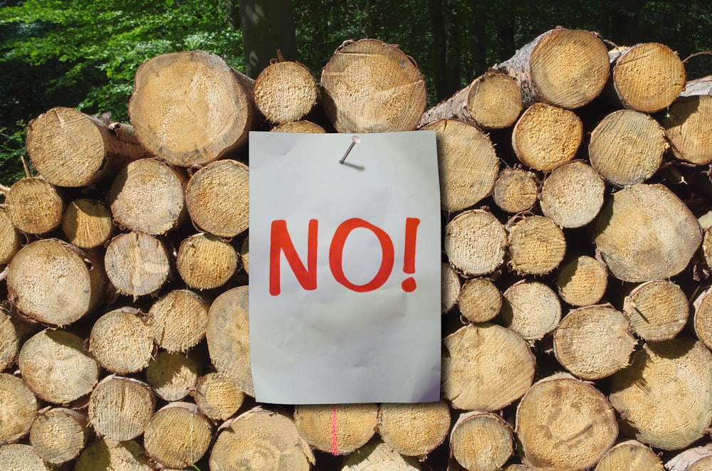 a sign that says no on a pile of logs