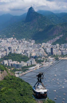 a cable car going up a mountain with a city in the background