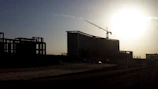 Heavy machinery at work constructing a new hotel foundation at sunrise.
