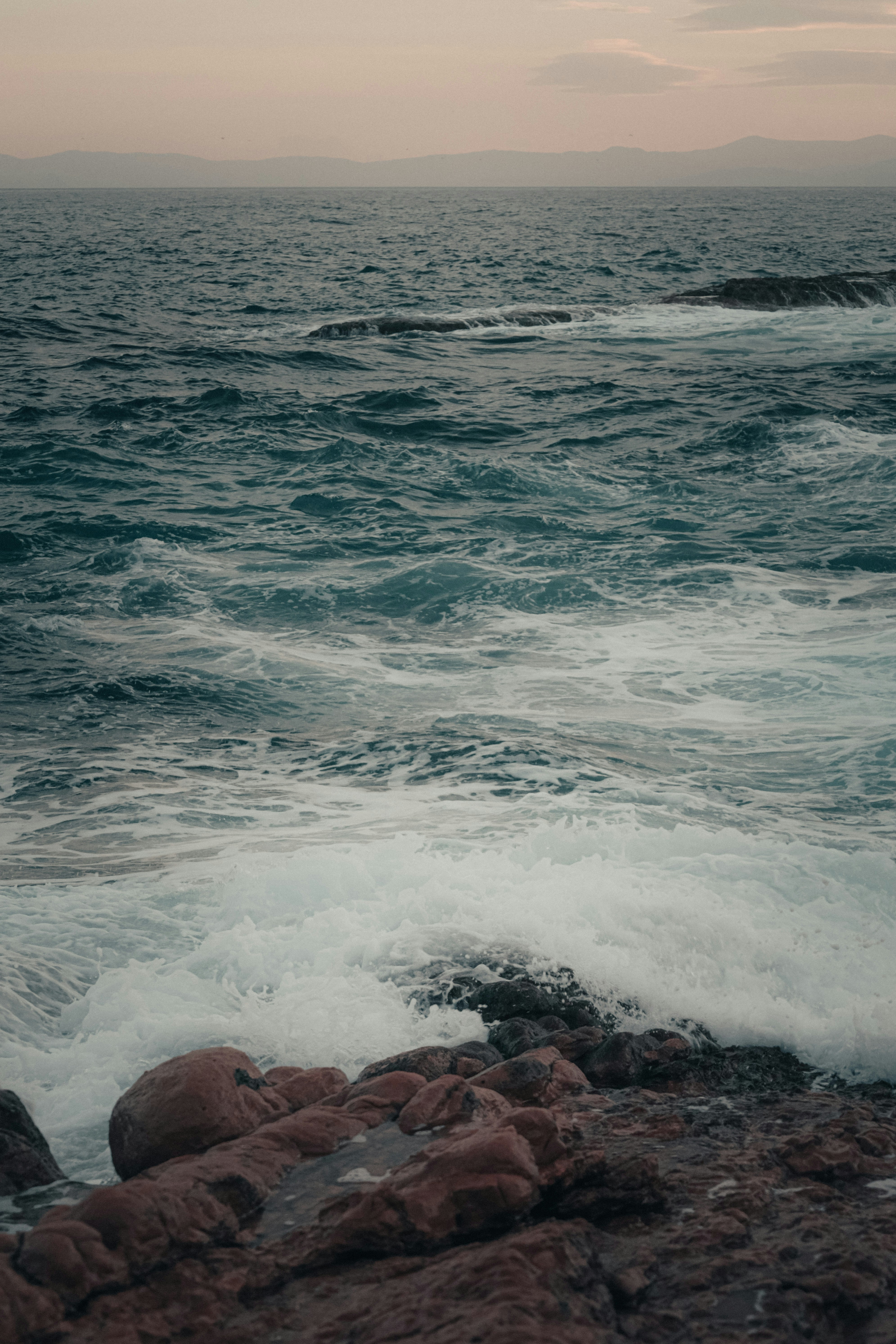 a person standing on top of a rocky beach next to the ocean