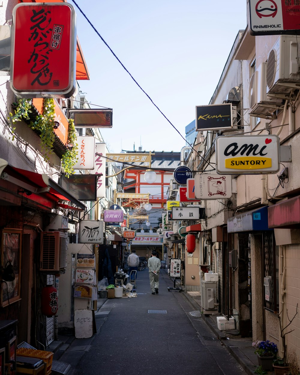 a narrow alley way with signs hanging from the buildings