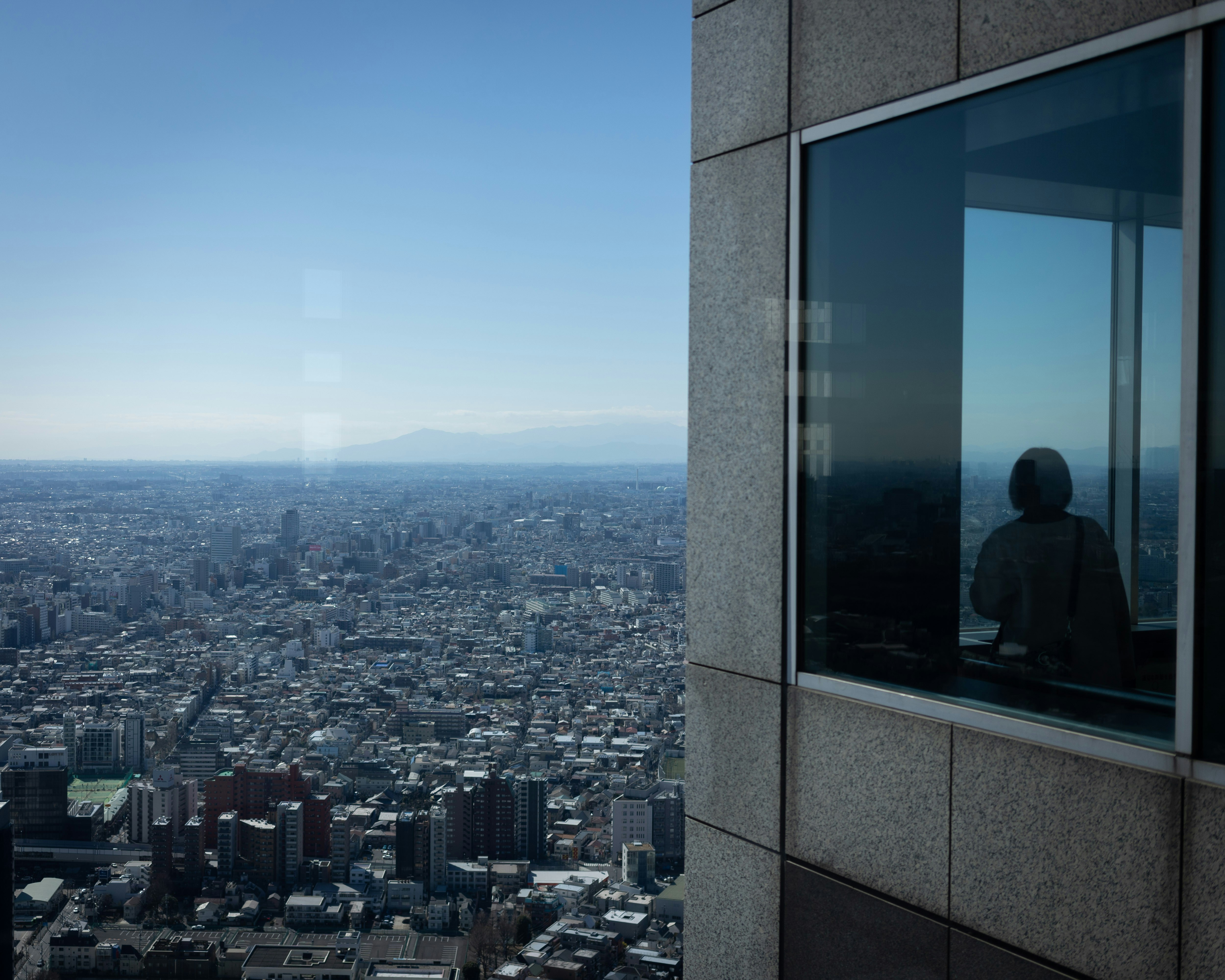 Image of a leader looking thoughtfully out of an office window over a city skyline - Faith based business leadership