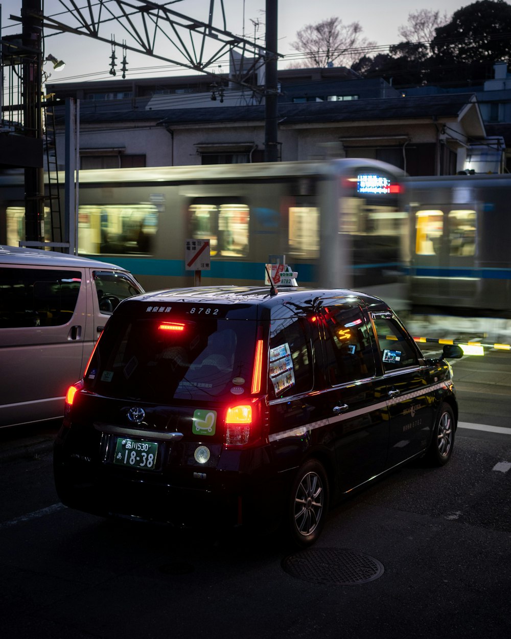 a black van driving down a street next to a train