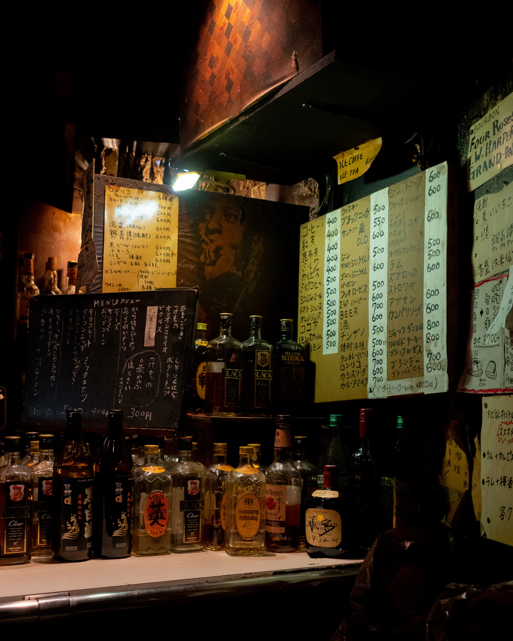 Dimly lit bar counter with shelves of liquor bottles
