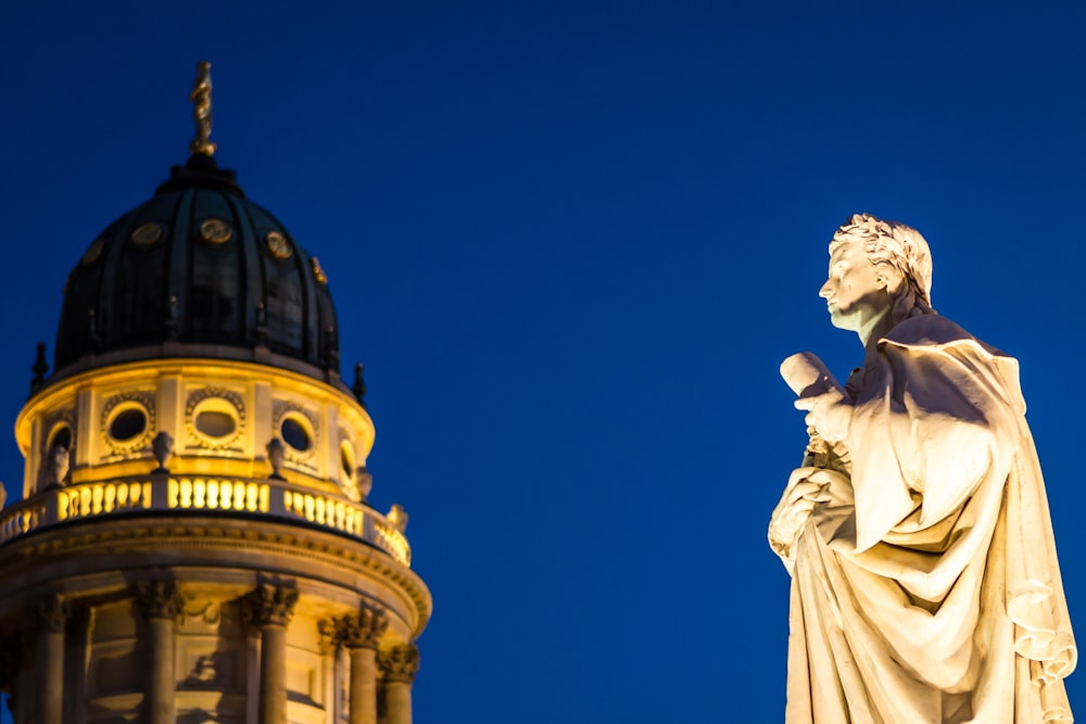 a statue of a man holding a book in front of a building