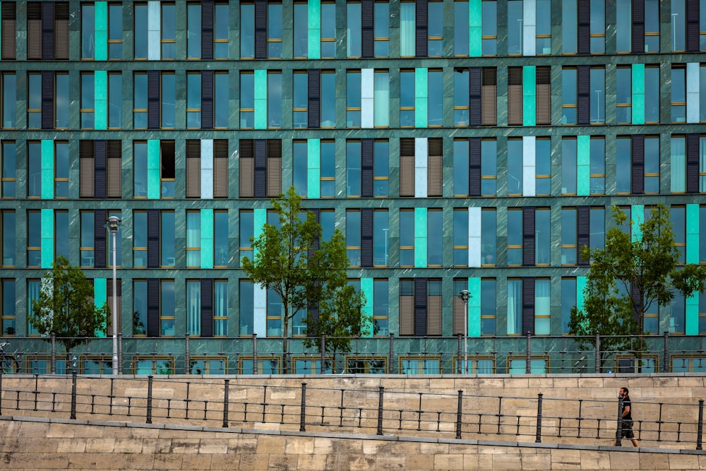 a man walking down a sidewalk in front of a tall building