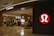A well-lit retail store featuring a modern and sleek entrance with prominent branding. The interior is visible with displays of clothing and accessories, suggesting an apparel store. The store has a structured layout and several mannequins.