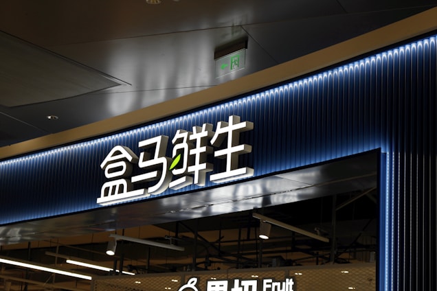 A store entrance with a prominent sign in Chinese characters, backlit by blue neon lights. The sign has a modern design with a clean and sleek appearance. Below the main sign, there is an additional English word 'Fruit', indicating the type of products available in the store.