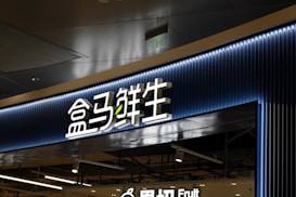 A store entrance with a prominent sign in Chinese characters, backlit by blue neon lights. The sign has a modern design with a clean and sleek appearance. Below the main sign, there is an additional English word 'Fruit', indicating the type of products available in the store.