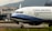An airplane with the branding of China Airlines is positioned on an airport tarmac. The aircraft is a commercial passenger jet, featuring a white and blue color scheme with the registration number B-18658 visible. In the background, there is a building with signage for China Airlines, indicating an airport setting with mountainous terrain in the distance.