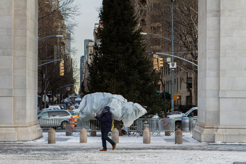 a man walking down a street carrying a large bag