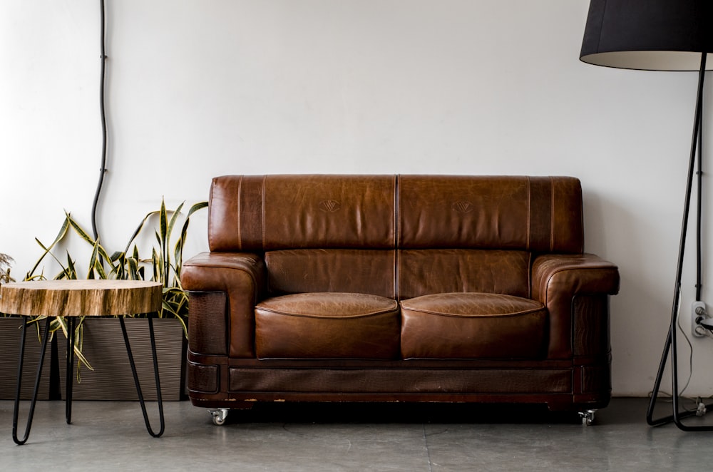 a brown leather couch sitting next to a wooden table