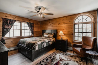 ceiling fan over a bed room with a neatly made bed and a chair