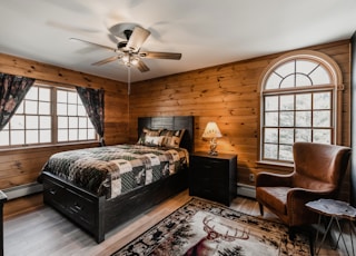 a bed room with a neatly made bed and a chair