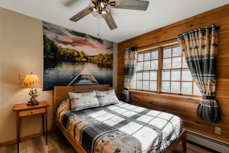 a bed sitting in a bedroom with a ceiling fan next to a window
