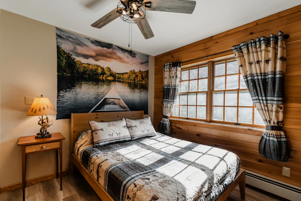 a bed sitting in a bedroom with a ceiling fan next to a window