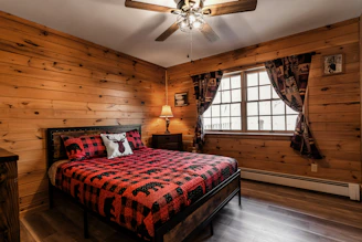 a bed in a room with wooden walls and a ceiling fan