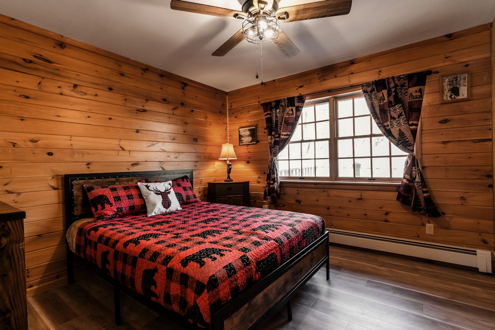 a bed in a room with wooden walls and a ceiling fan