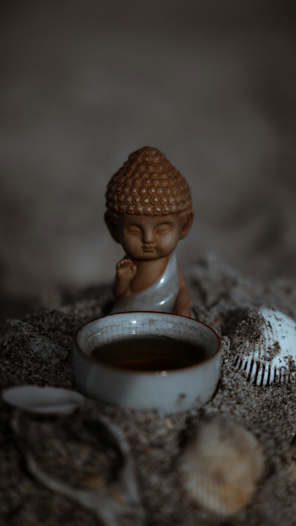 a small buddha statue sitting next to a bowl of soup