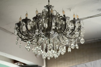 A luxurious, intricate chandelier is hanging from the ceiling, adorned with numerous crystal pendants and ornate metalwork. The chandelier features several bulb sockets shaped like candles, contributing to a classic and elegant appearance. The crystals catch and reflect light, adding a touch of sparkle.
