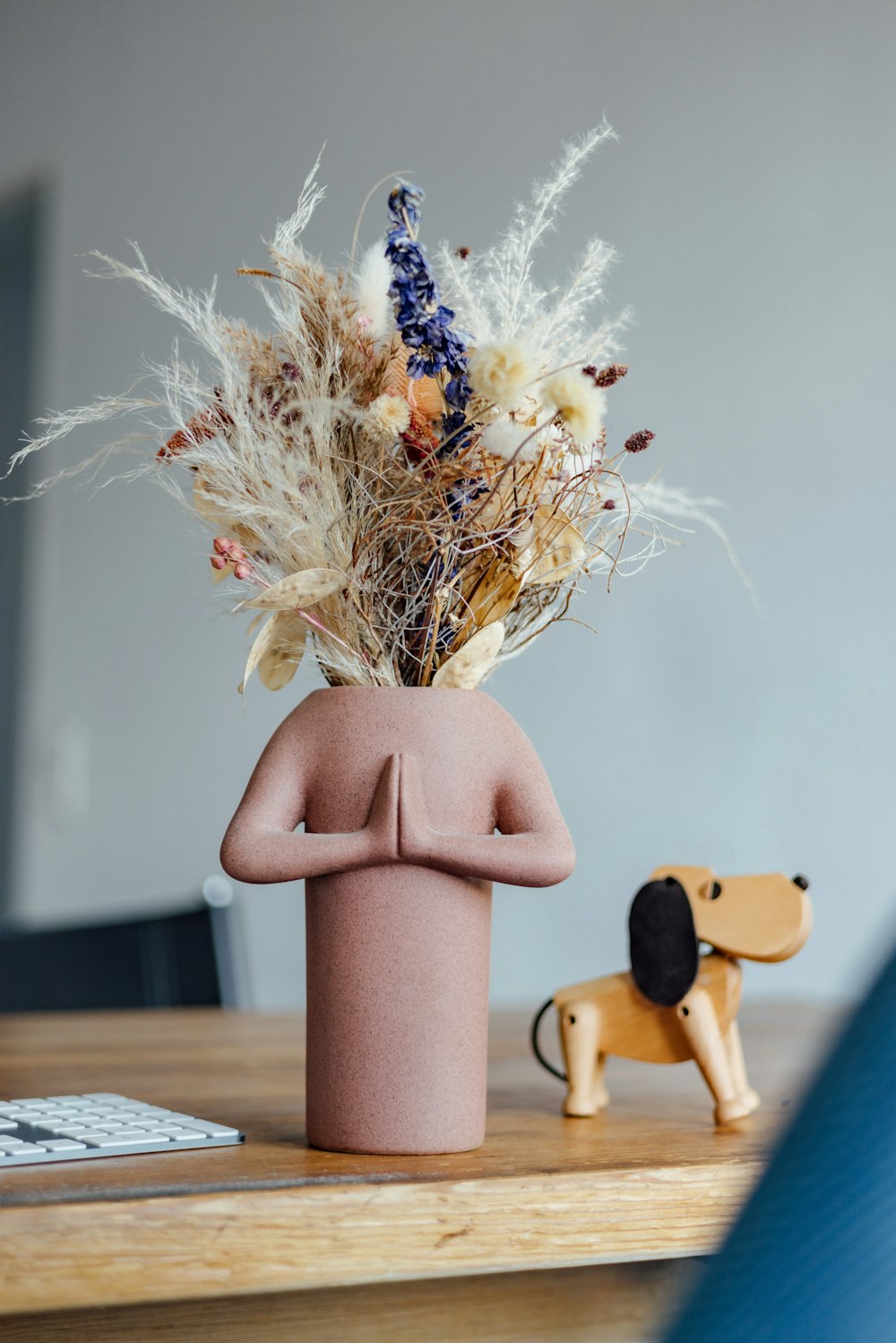 a vase with dried flowers and a dog figurine