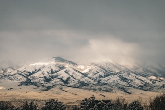 a snow covered mountain range under a cloudy sky