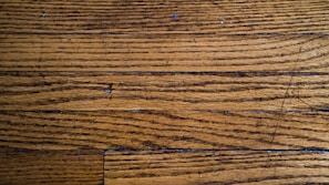 Wooden floor planks with visible grain and texture, featuring some scratches and imperfections.