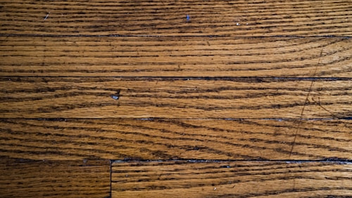 Wooden floor planks with visible grain and texture, featuring some scratches and imperfections.