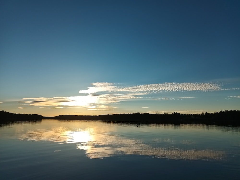 the sun is setting over a calm lake