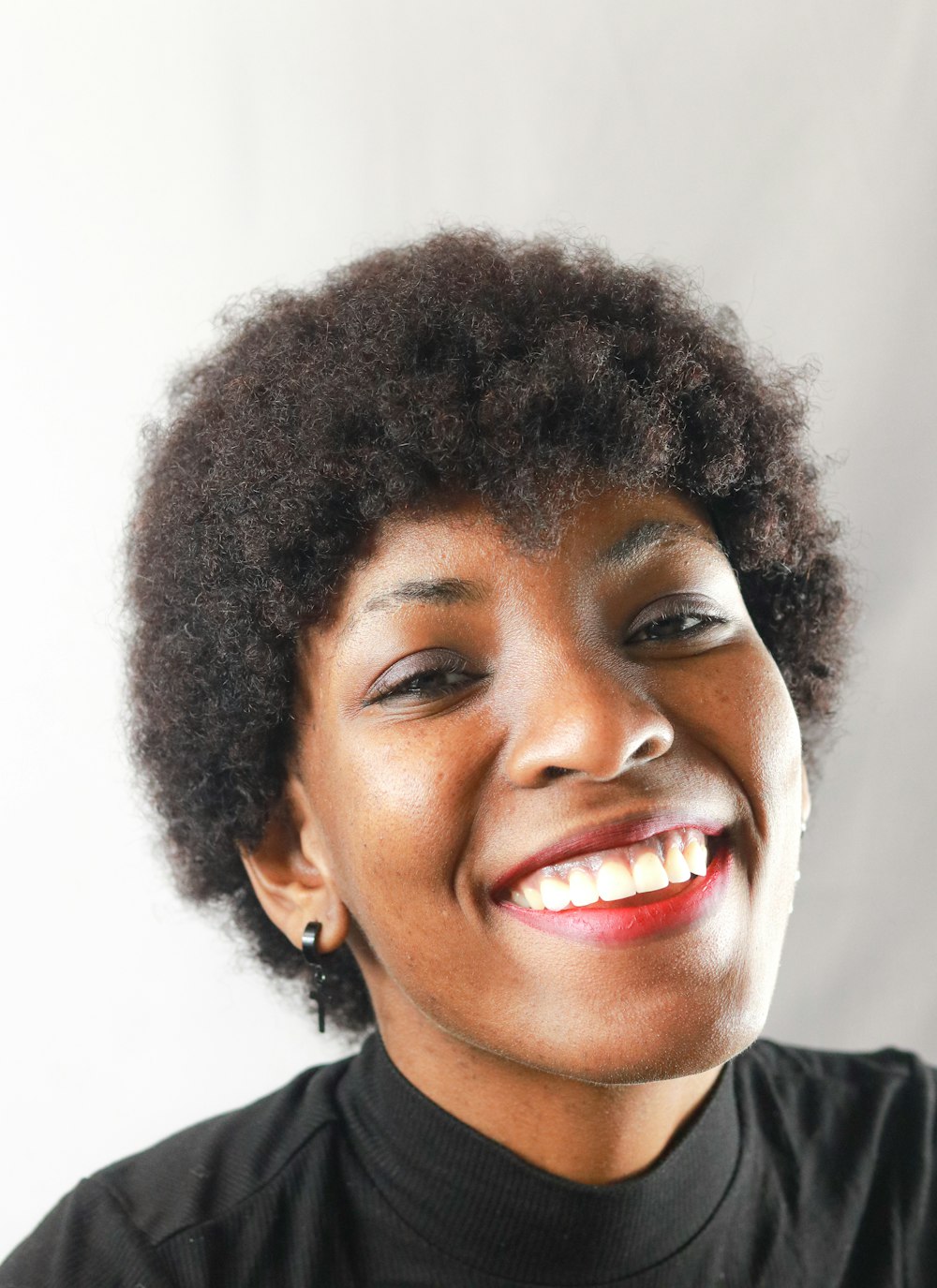 Una donna con un sorriso afro per la macchina fotografica