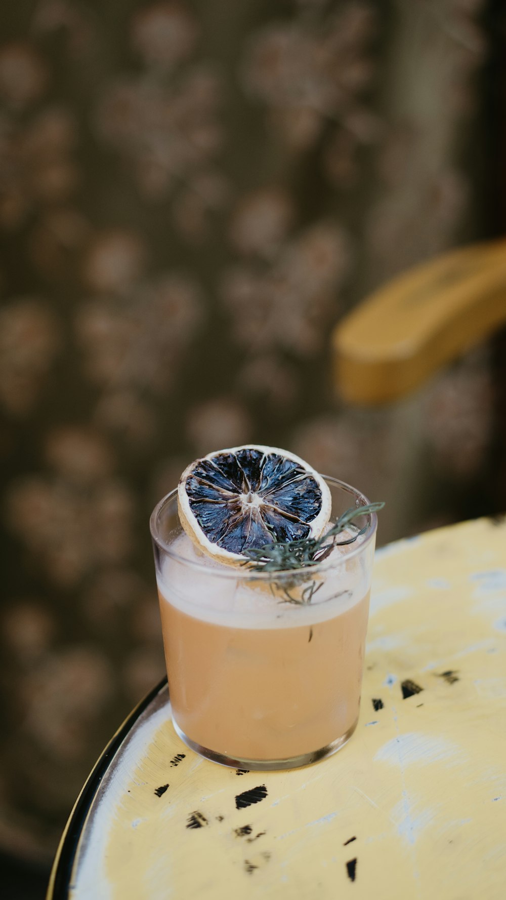 a glass with a drink on top of a table