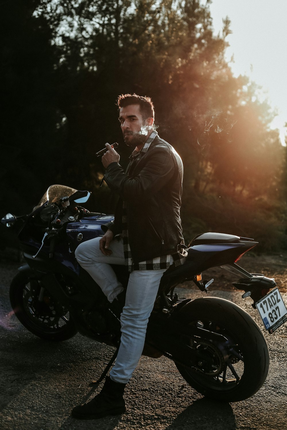 a man sitting on a motorcycle smoking a cigarette