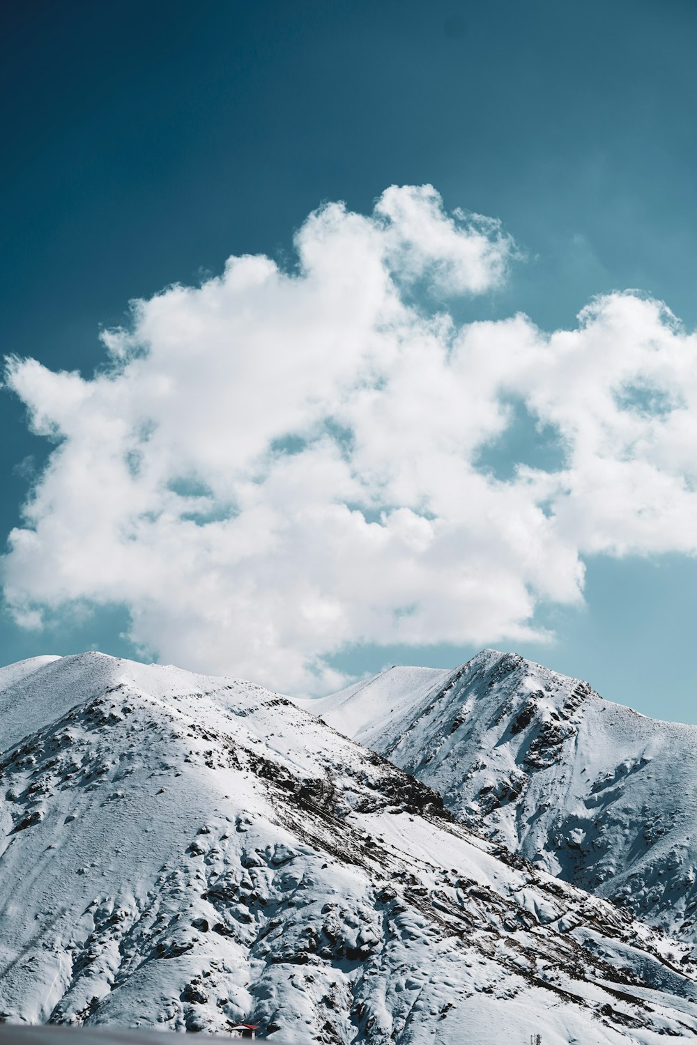 a snow covered mountain under a cloudy blue sky