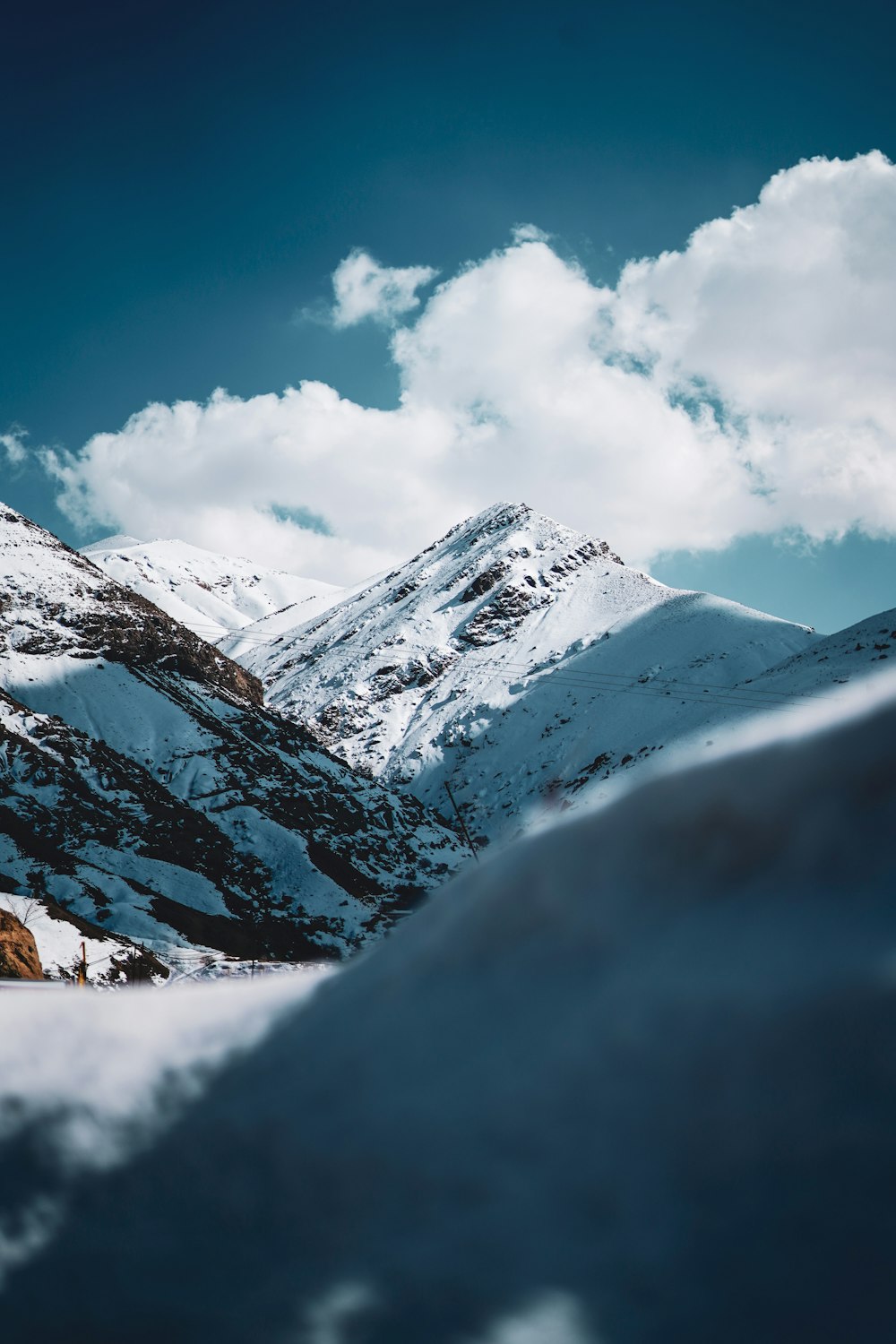 a snow covered mountain range under a cloudy blue sky