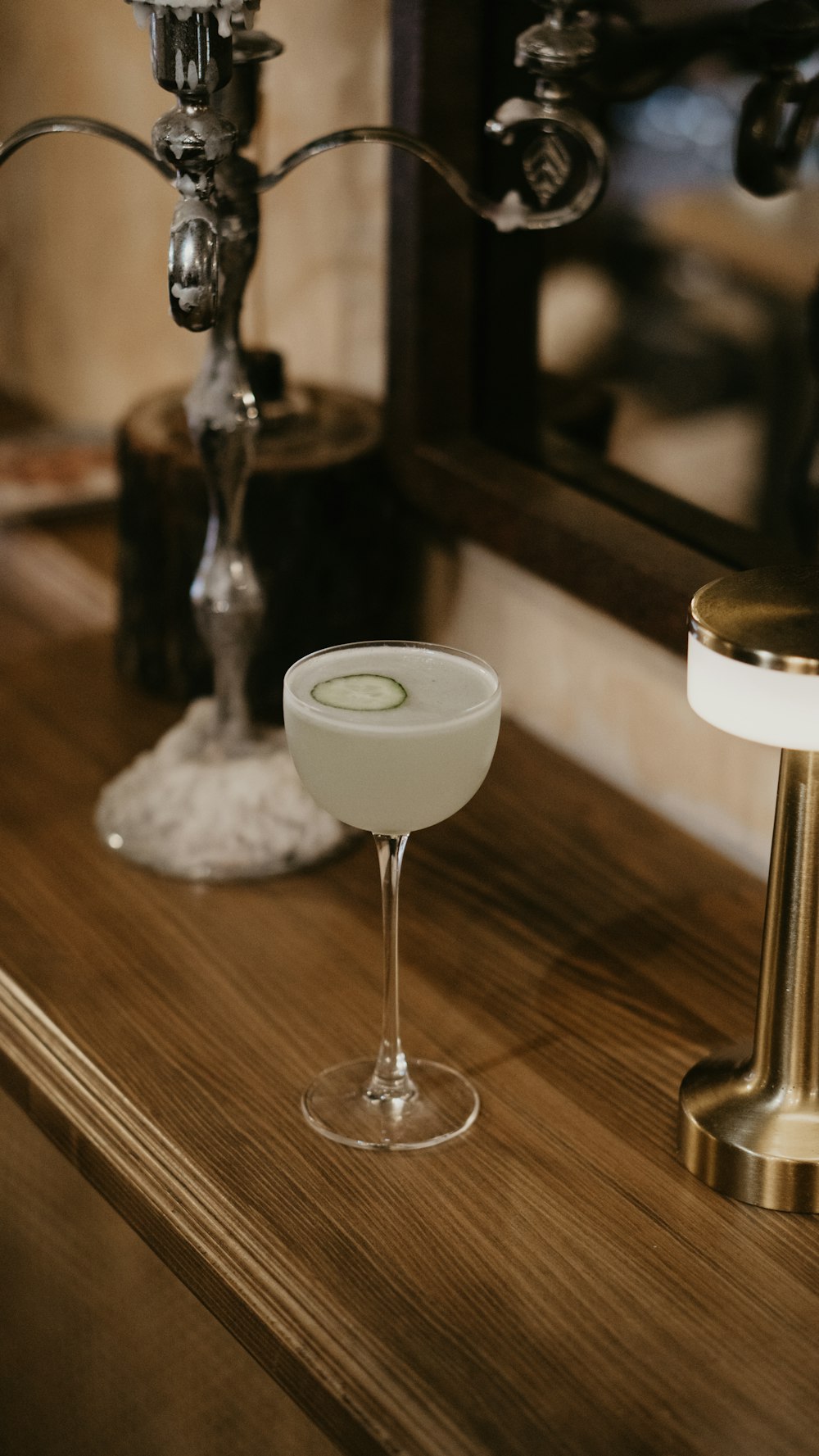 a table topped with a martini glass next to a lamp