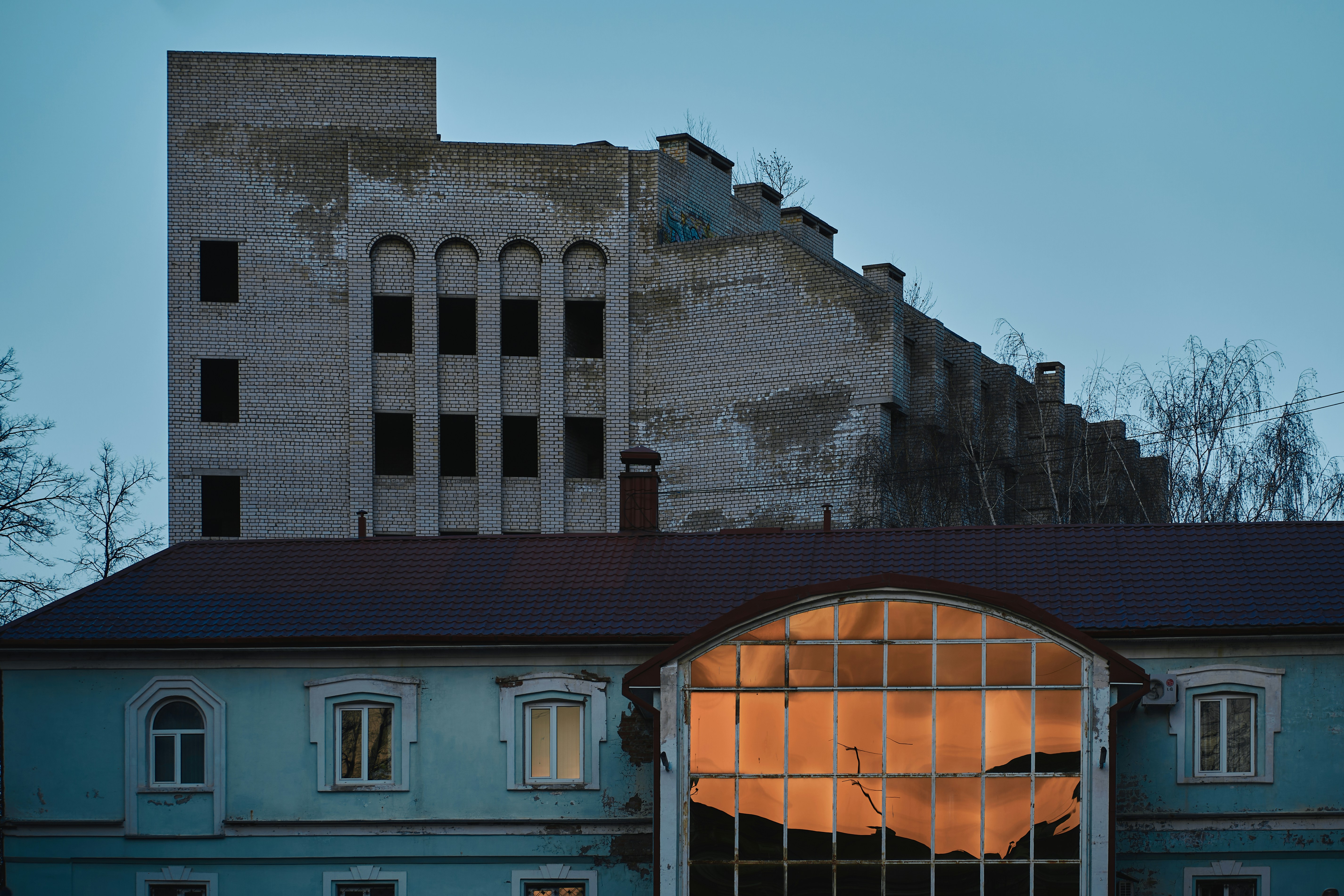 an old building with a large window and a rusted roof (Photo by Maxim Tolchinskiy on Unsplash)