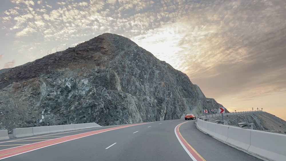 Un'auto che guida lungo una strada vicino a una montagna