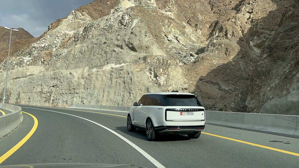 a white range rover driving down a mountain road
