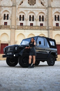 a woman standing next to a black mercedes benz benz benz benz benz benz benz benz