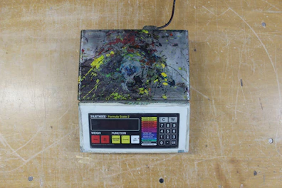 Compact portable kitchen scale with a bright LCD screen on a marble surface.