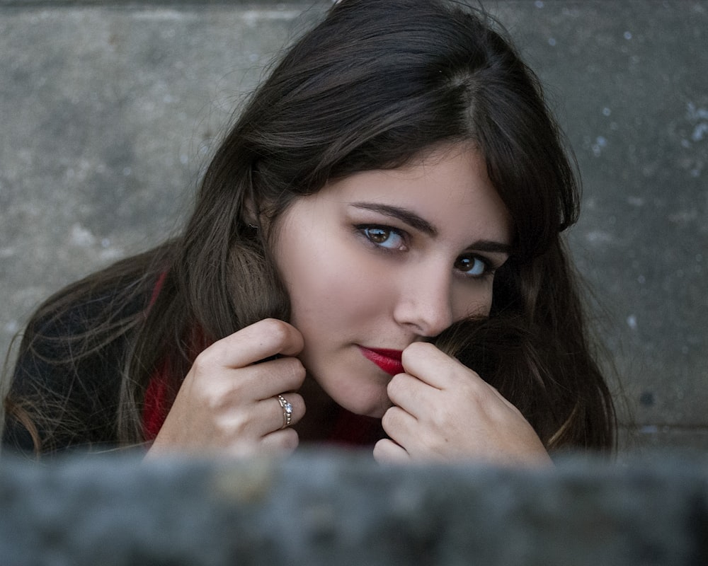 a woman with a ring on her finger leaning against a wall