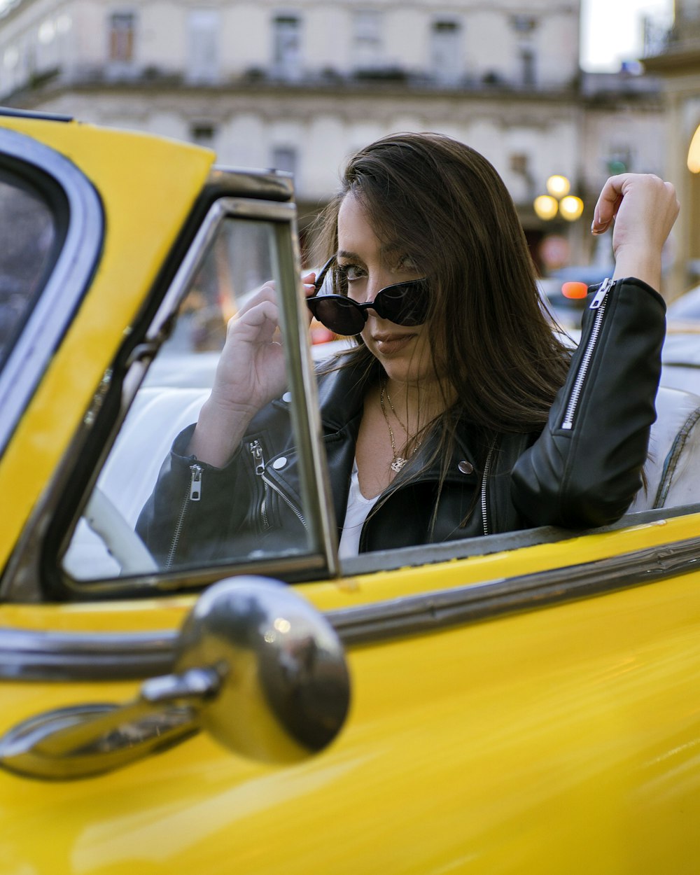 a woman sitting in a yellow car talking on a cell phone