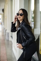Close-up of a woman wearing a chic leather jacket with bold accessories in an urban setting.