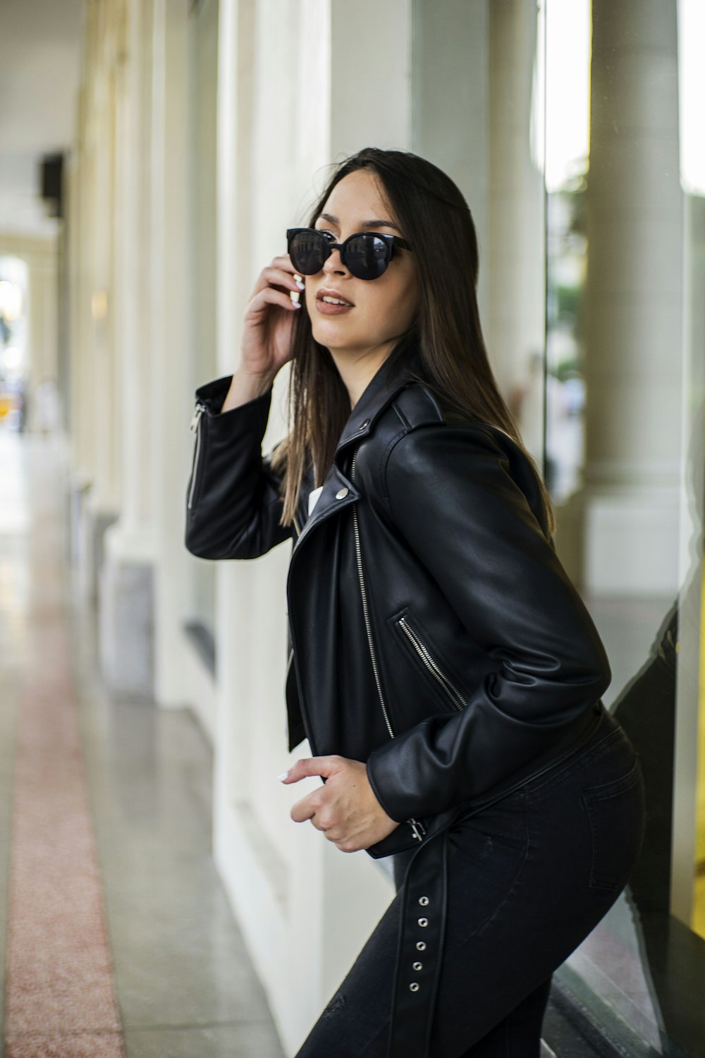 a woman in a black leather jacket is talking on a cell phone