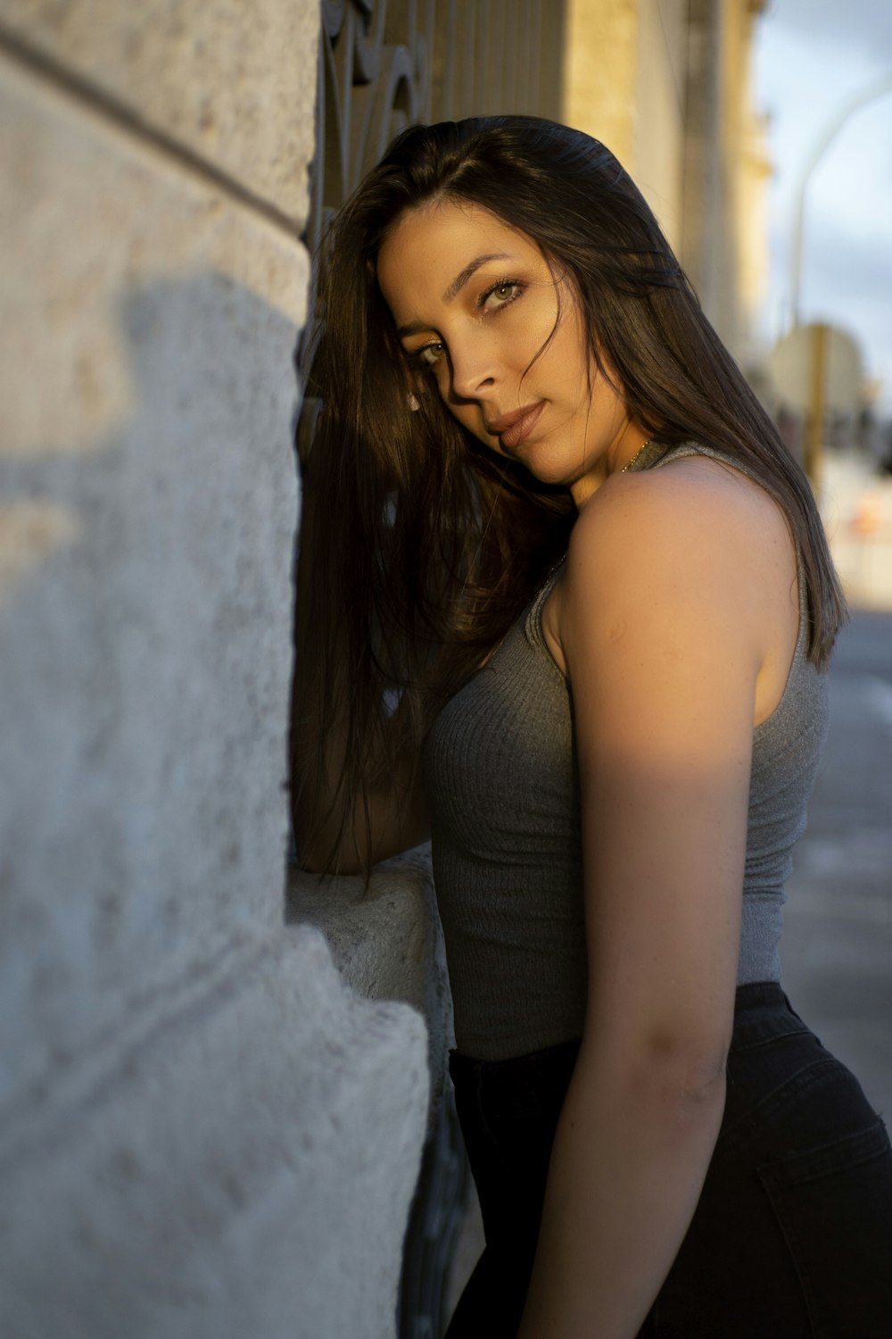 a beautiful young woman leaning against a wall