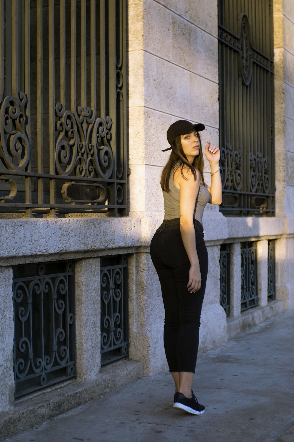 a woman in a hat is standing on a sidewalk